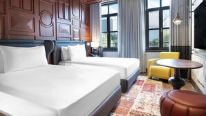 A hotel room with two beds, a small round table, a yellow armchair, and a large window with curtains. - Canopy By Hilton Istanbul Taksim (Istanbul)