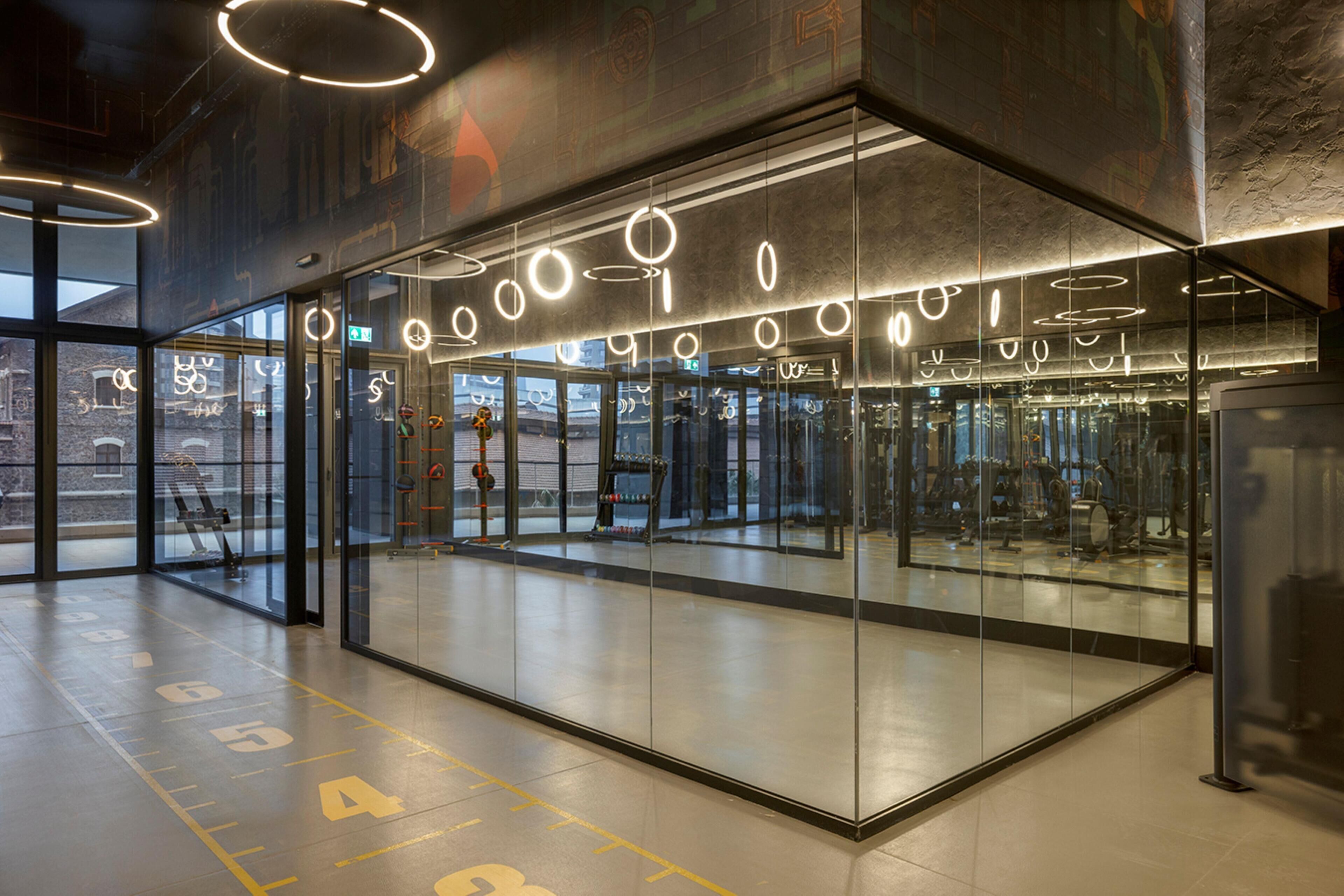 A modern gym with glass walls, exercise equipment, and a clean, well-lit interior.