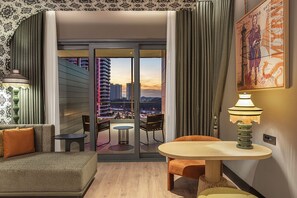 Een moderne hotelkamer met balkon, een bank, een tafeltje en een lamp.