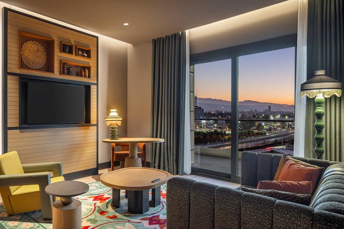 Une chambre d’hôtel moderne avec vue sur la ville, un coin repas et un espace salon confortable.