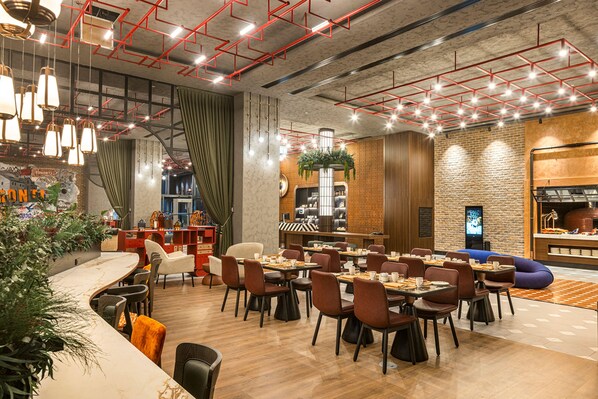 A modern restaurant with a high ceiling, exposed beams, and a mix of seating arrangements including tables and booths.