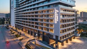 Ein mehrstöckiges Hotel im modernen Stil, mit einem gut sichtbaren Schild 'canopy by Hilton', einer großzügigen Lobby und einem Parkplatz.