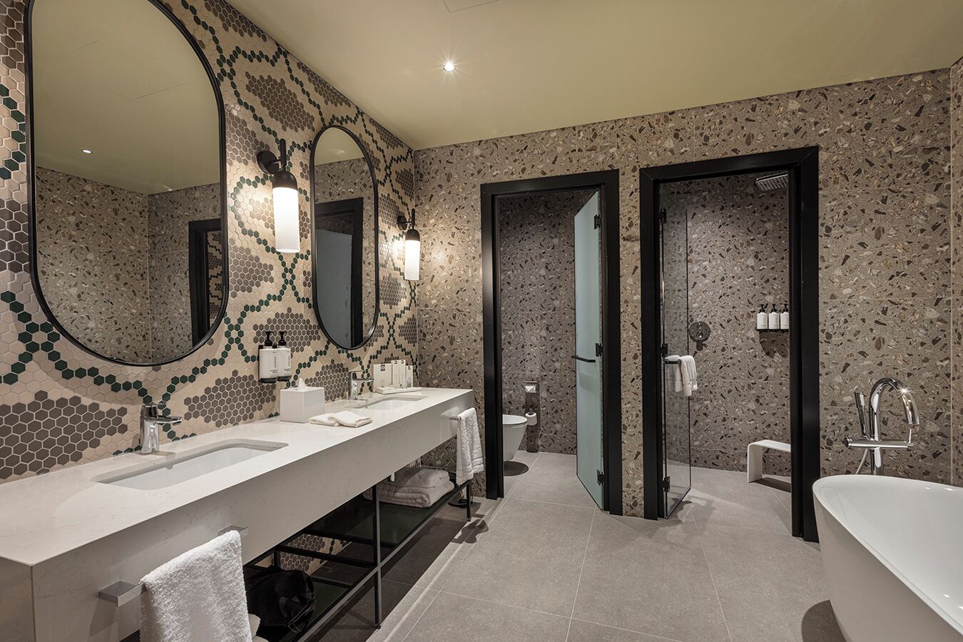 Un baño moderno con dos lavamanos, un espejo grande y una zona de ducha.