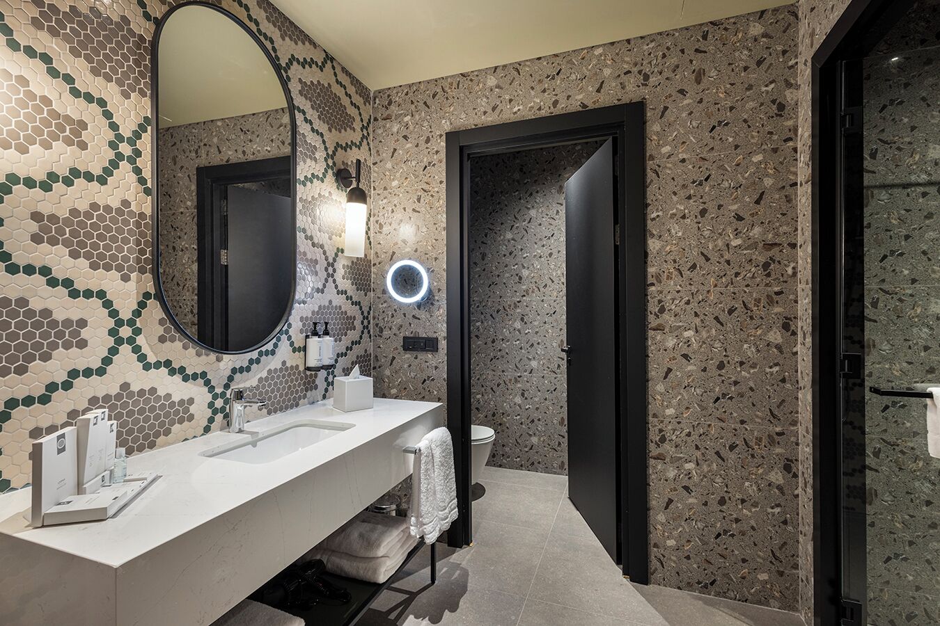 Een moderne badkamer met een witte wastafel, een grote spiegel en een structuurwand.