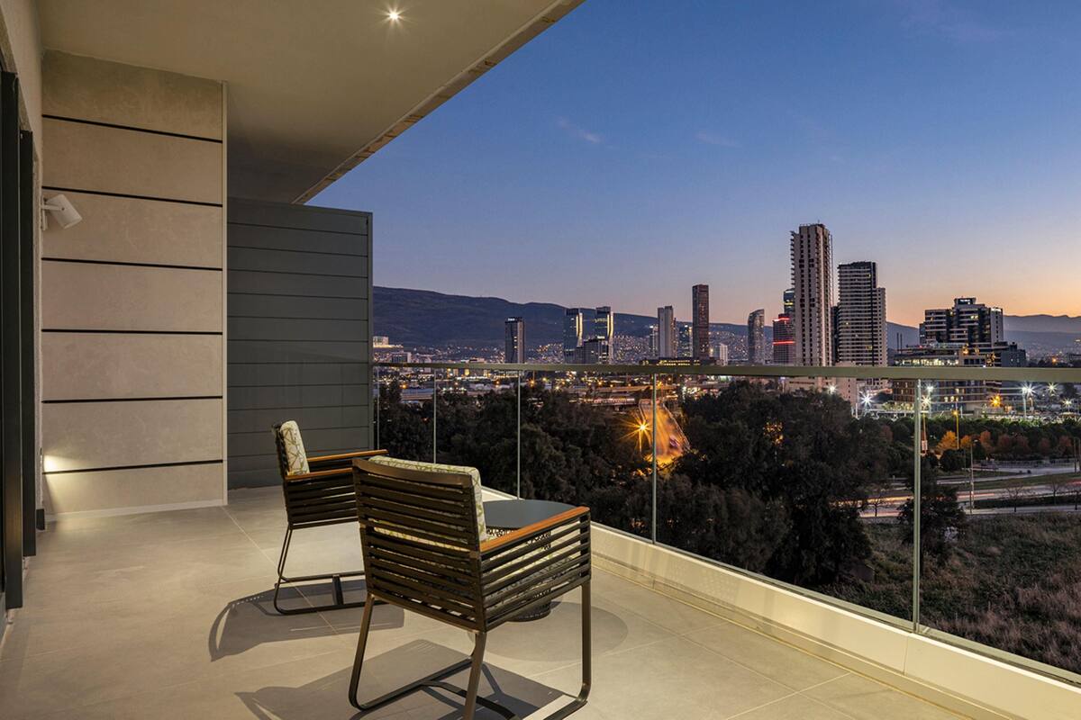 Un balcon avec deux chaises et une table, donnant sur une vue de la ville au crépuscule.