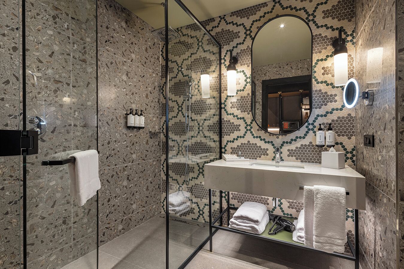 Un baño moderno con ducha envuelta en vidrio, un espejo grande y un tocador con lavamanos.