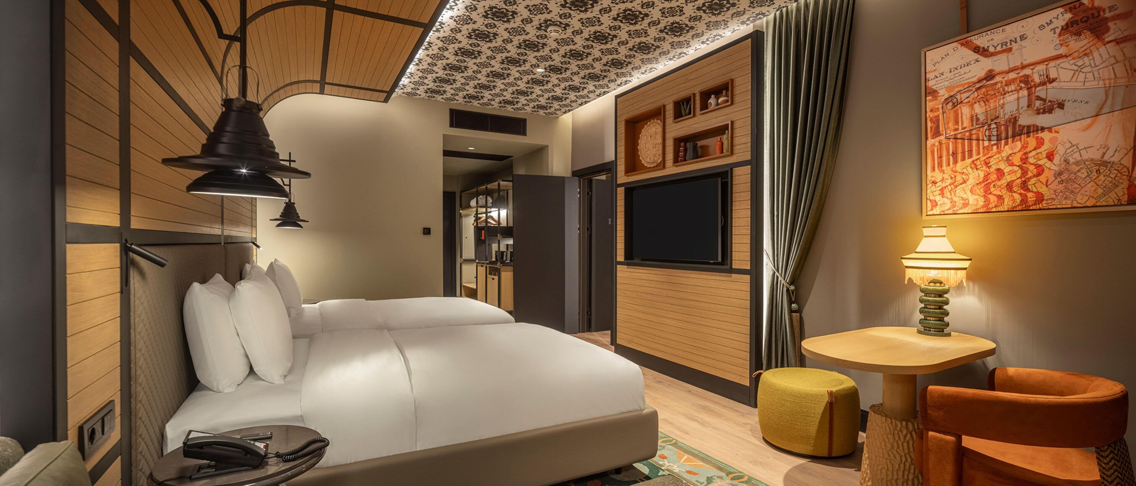 A modern hotel room with a bed, bedside table, lamp, and a map on the wall.