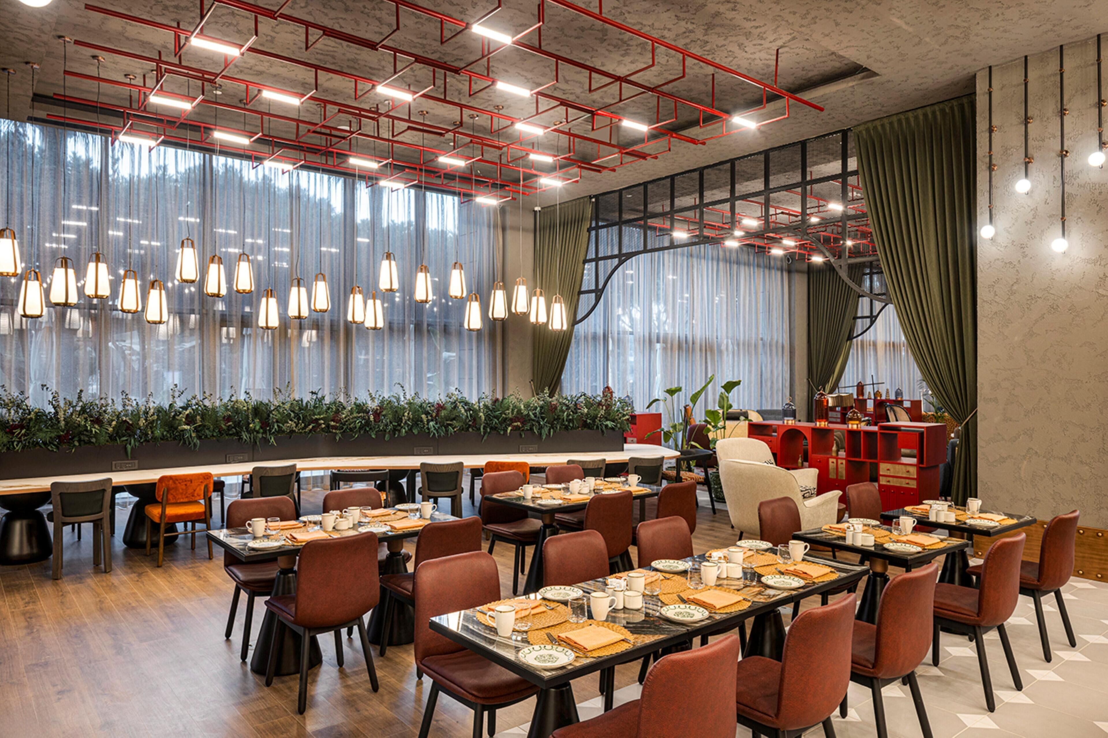 A spacious dining area with long tables, chairs, and hanging pendant lights.