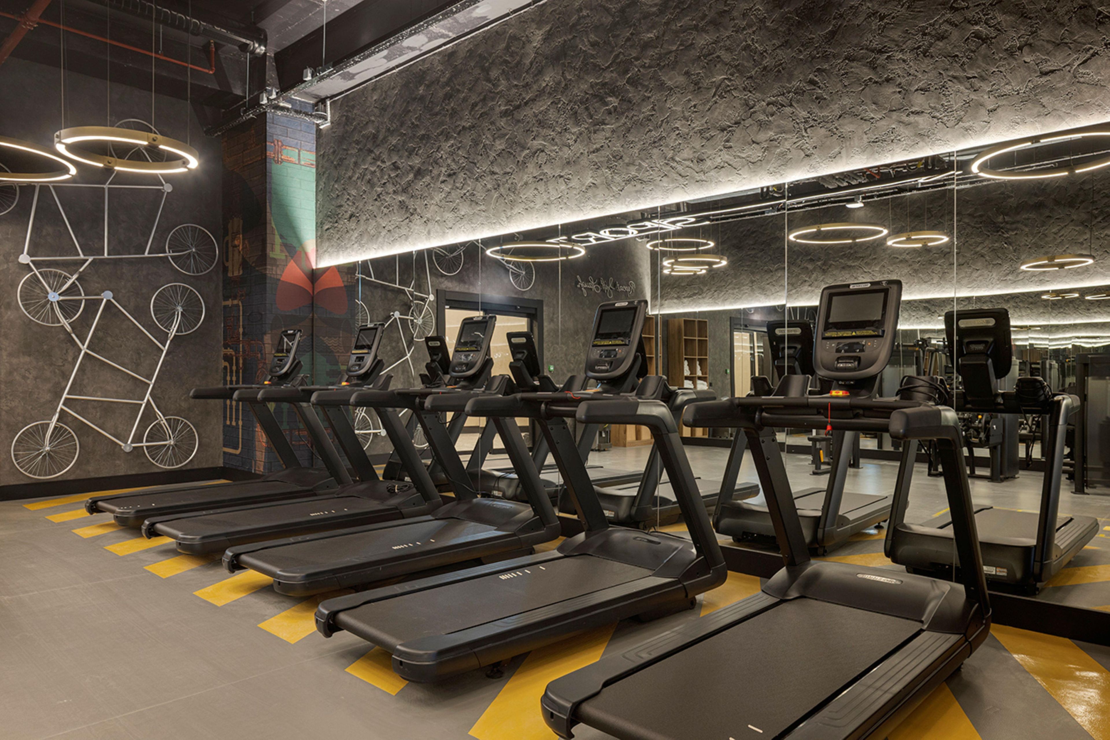 Un gimnasio con numerosas cintas de correr, bicicletas estáticas y máquinas de cardio.