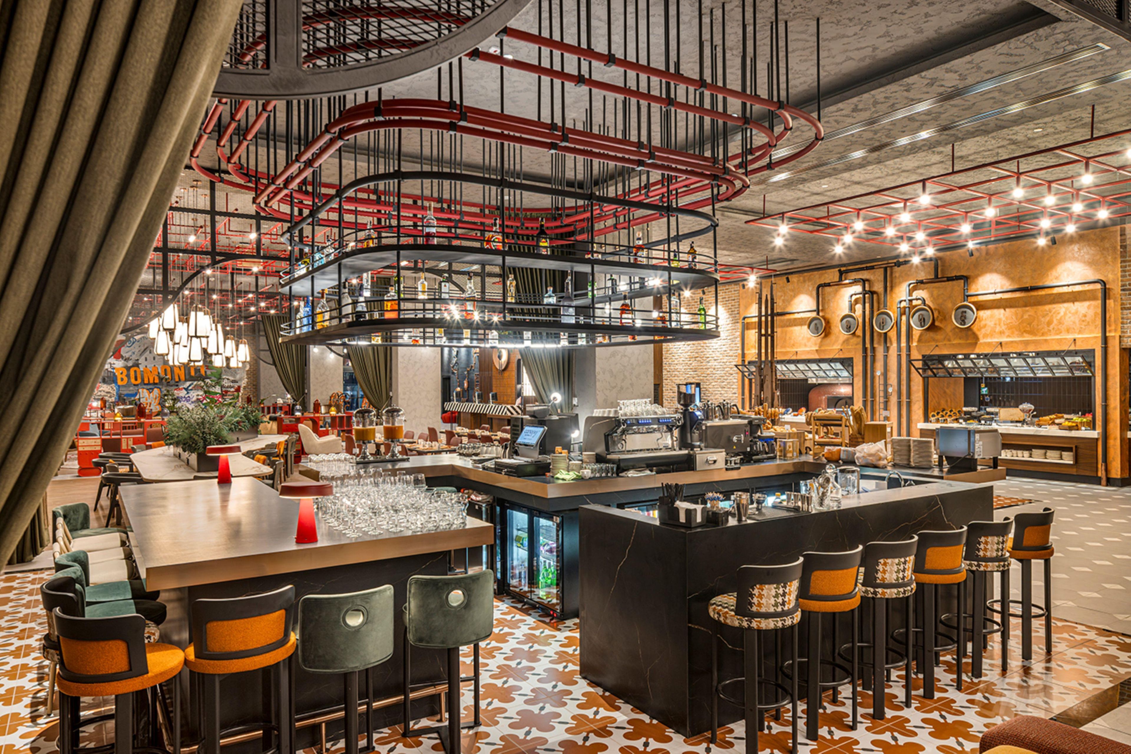 A modern bar area with a central bar, seating, and a unique ceiling design.