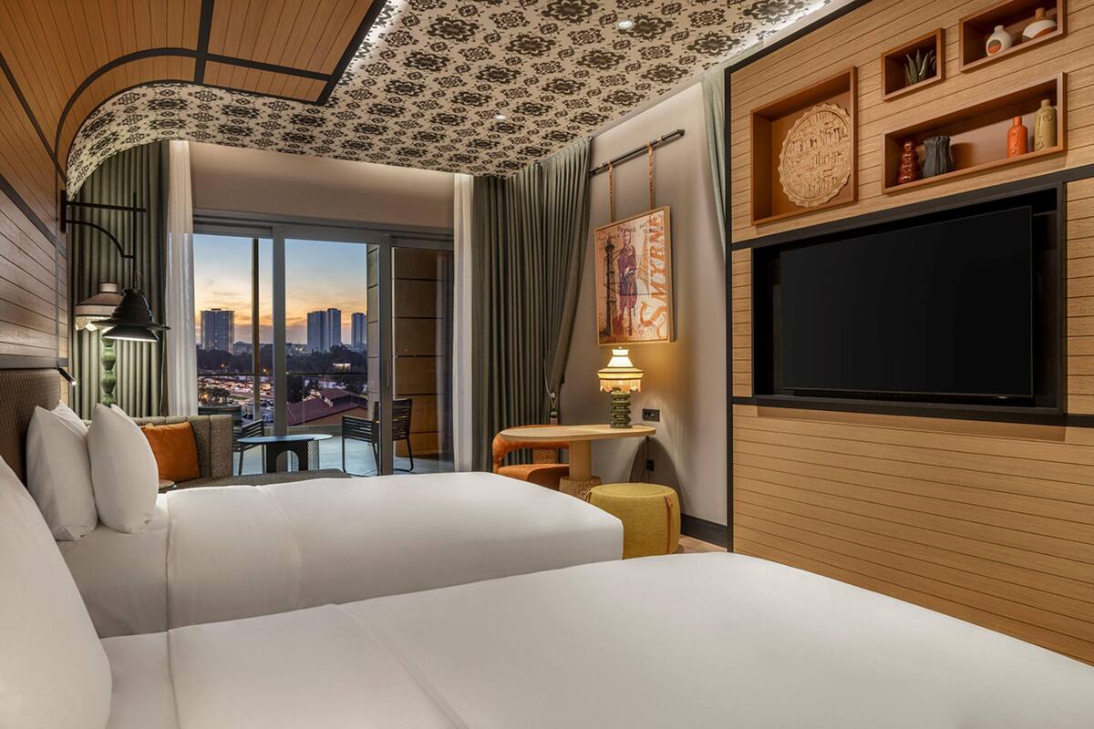 Une chambre d’hôtel moderne dotée d’un grand lit, d’une télévision, d’une vue sur la ville et d’un balcon.