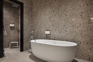 Un baño moderno con una bañera independiente, un cabezal de ducha y un pequeño banco.
