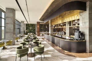 Un amplio hall de hotel con una recepción curva, zonas de estar y vistas al interior.
