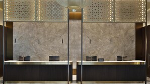 Un área de recepción moderna con paredes de mármol, dos mostradores y un techo decorativo.