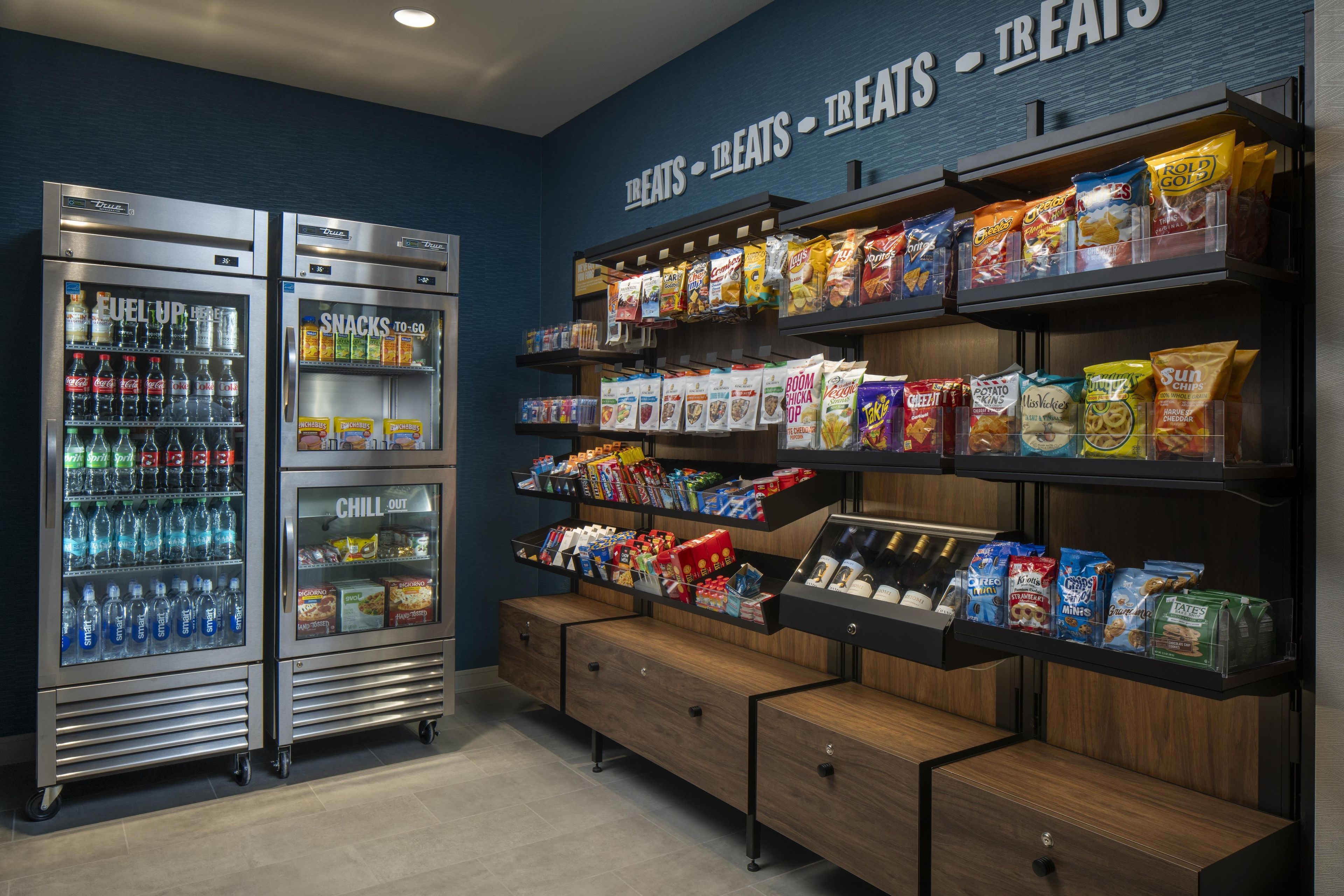A snack and beverage vending area with multiple shelves stocked with various snacks and drinks.