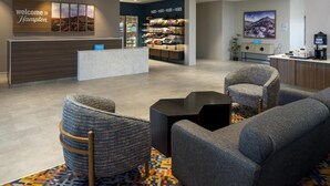 Un vestíbulo de hotel con mostrador de recepción, zona de estar y bar de aperitivos.