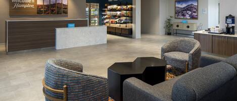 A hotel lobby with a reception desk, seating area, and a snack bar.