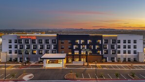 Un hotel de varios pisos con un diseño moderno, destacando la señalización de Hampton Inn & Suites by Hilton.