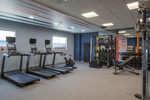 Un gimnasio con cintas de correr, elípticas y equipo de levantamiento de pesas.