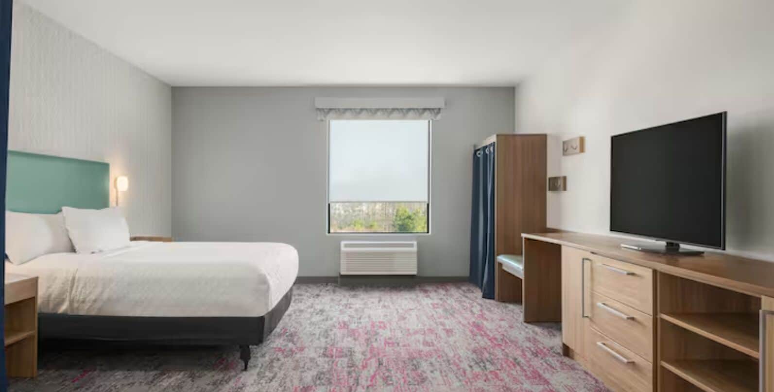 Una habitación de hotel con cama, televisión, escritorio y ventana.