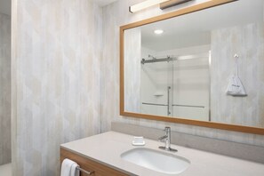 Un baño con un espejo grande, un lavabo y una ducha.