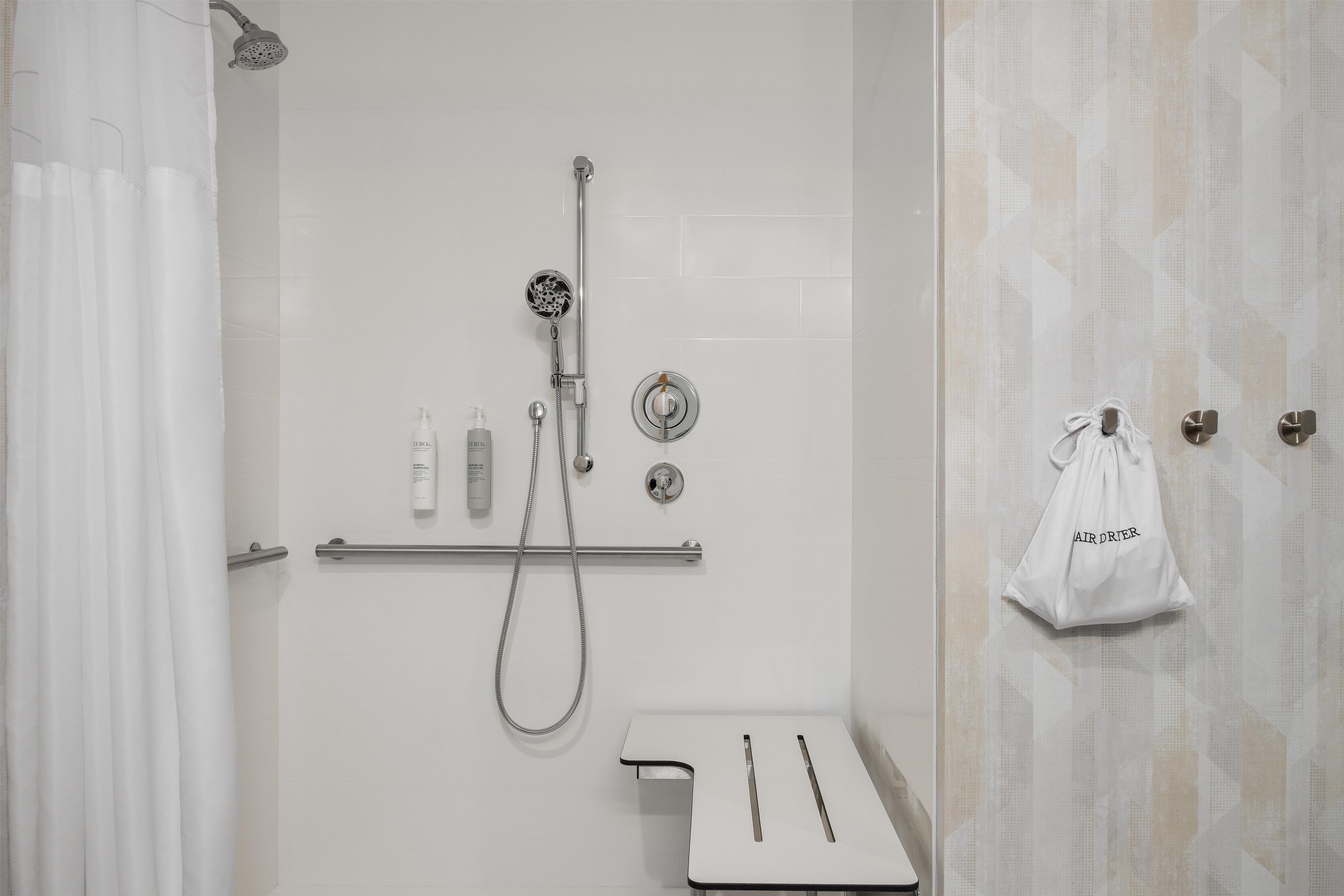 A modern bathroom with a shower, toilet, and towel rack.