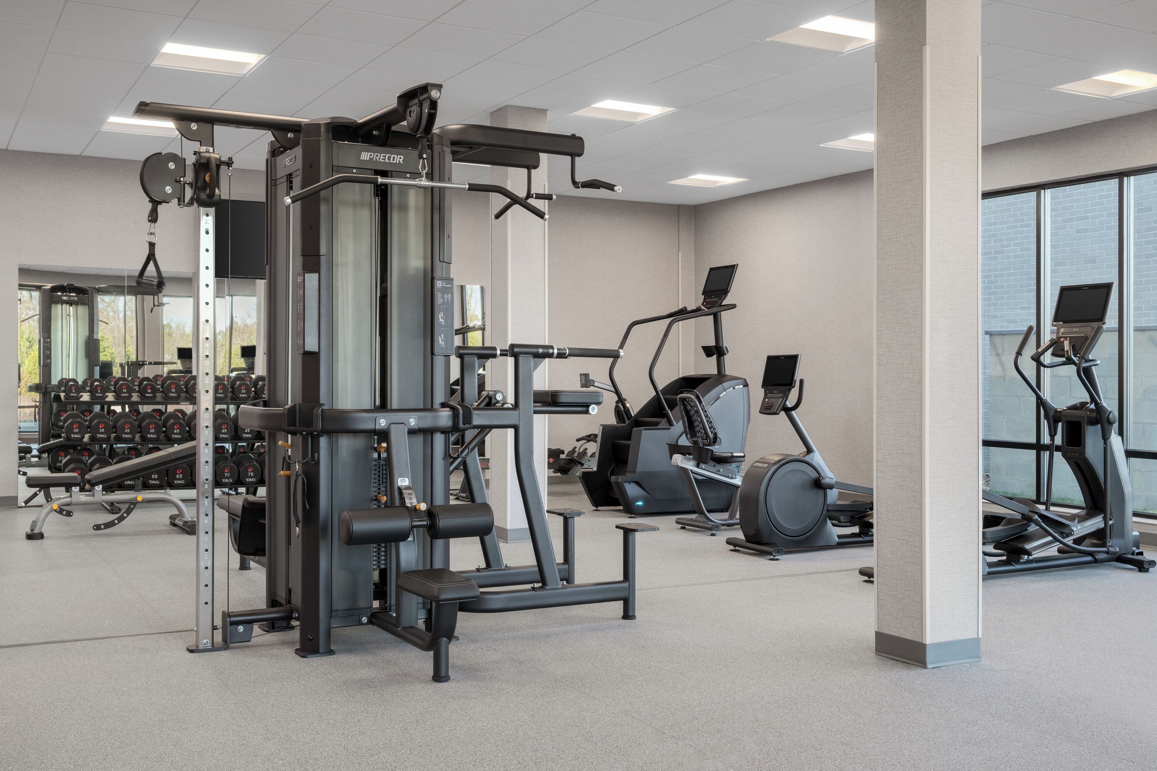 A gym with various exercise equipment, including a weight machine, treadmills, and dumbbells.