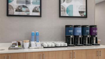 Eine Kaffeestation mit mehreren Spendern, verschiedenen Einwegbechern und Geschirr.