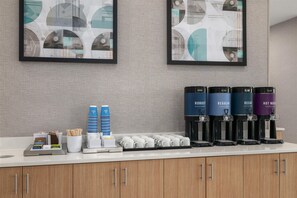 Una estación de café con varios dispensadores y una variedad de vasos y utensilios desechables.