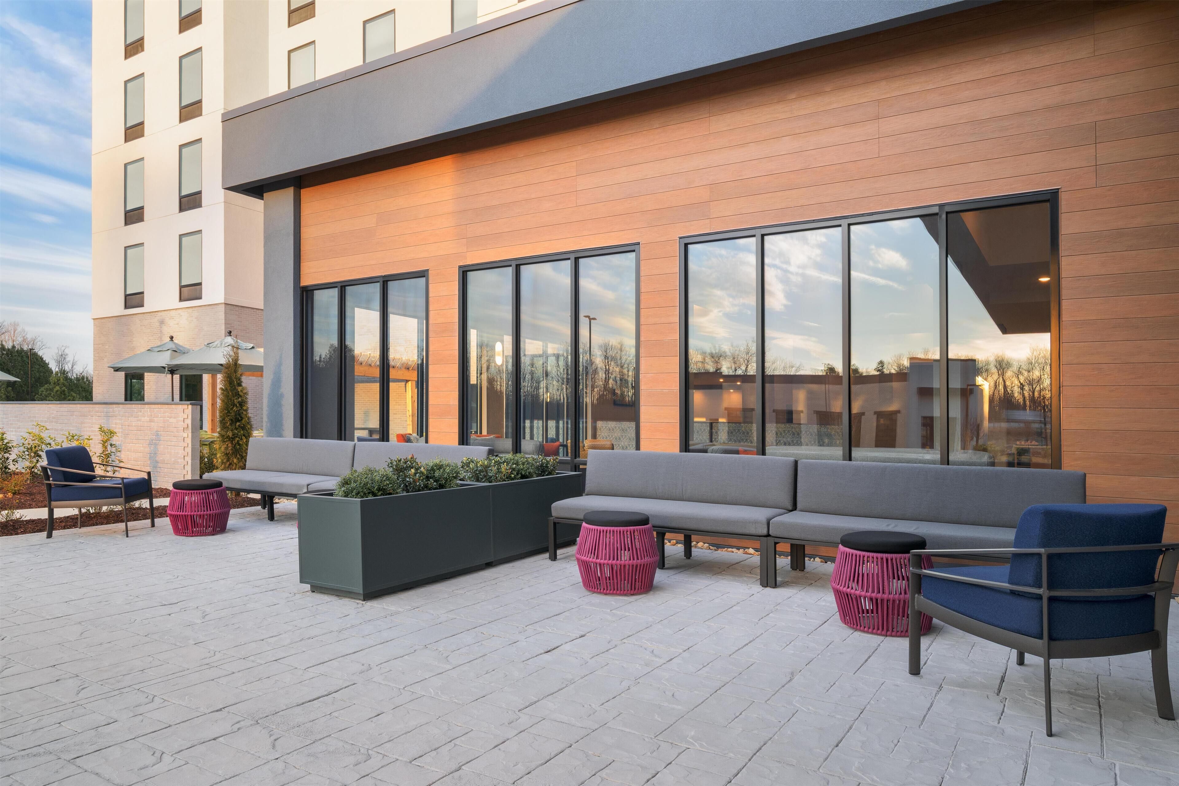 A modern outdoor seating area with a sofa, chairs, and planters.