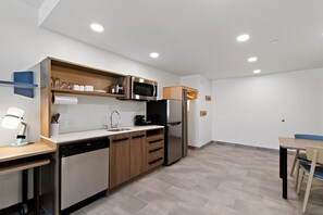 A modern kitchen with built-in appliances, a dishwasher, and a dining area with a table and chairs.