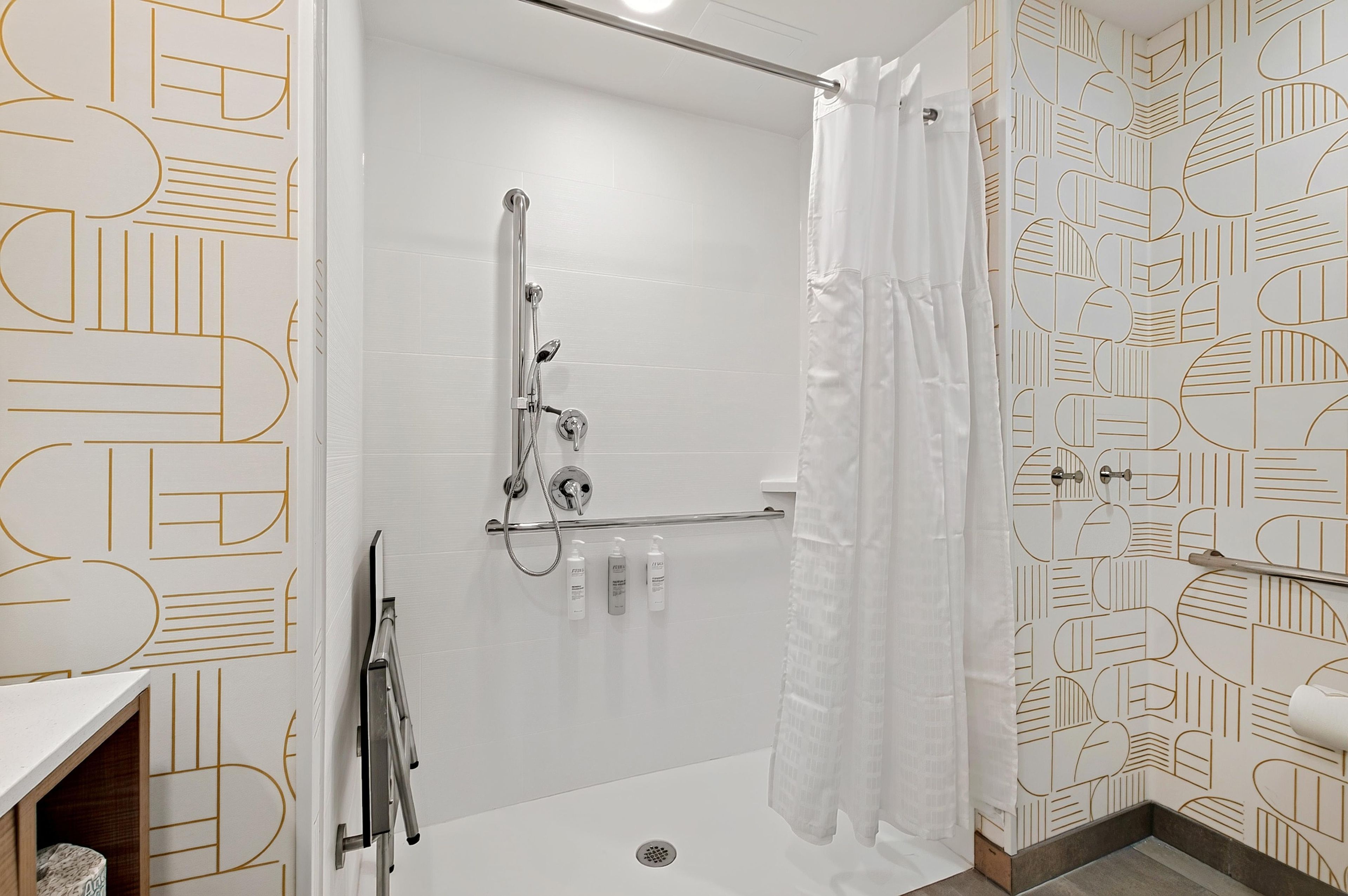 A modern bathroom with a shower, a handrail, and a patterned wall.