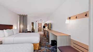 A hotel room with a large bed, a desk, a chair, a television, and a bathroom visible through an open door.