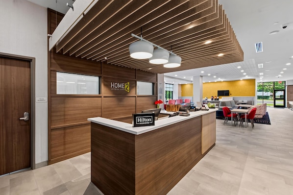 A hotel reception area with a wooden reception desk, a sign for 'Hilton Honors', and a modern interior design. - Home2 Suites By Hilton Raleigh Crabtree (Raleigh)