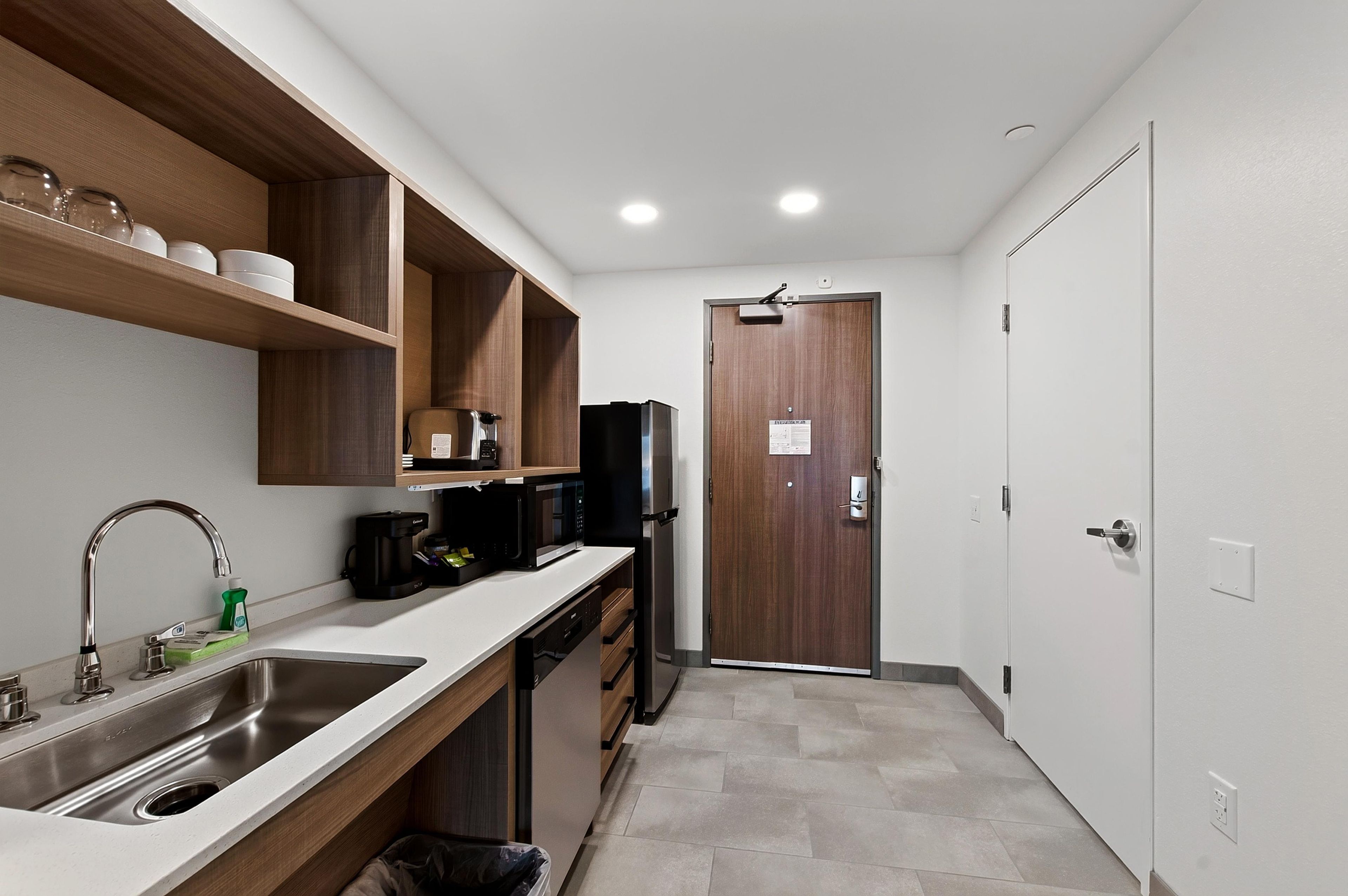 A compact kitchen with a sink, microwave, and coffee maker.