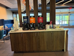 Ein Kaffee-Bereich mit verschiedenen Automaten für Getränke, einem Warmwassergerät und einer Kaffeemaschine.