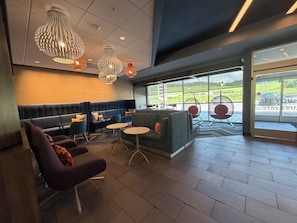 Un espacio lounge moderno con disposiciones de asientos, vistas por ventanas amplias y lámparas decorativas.