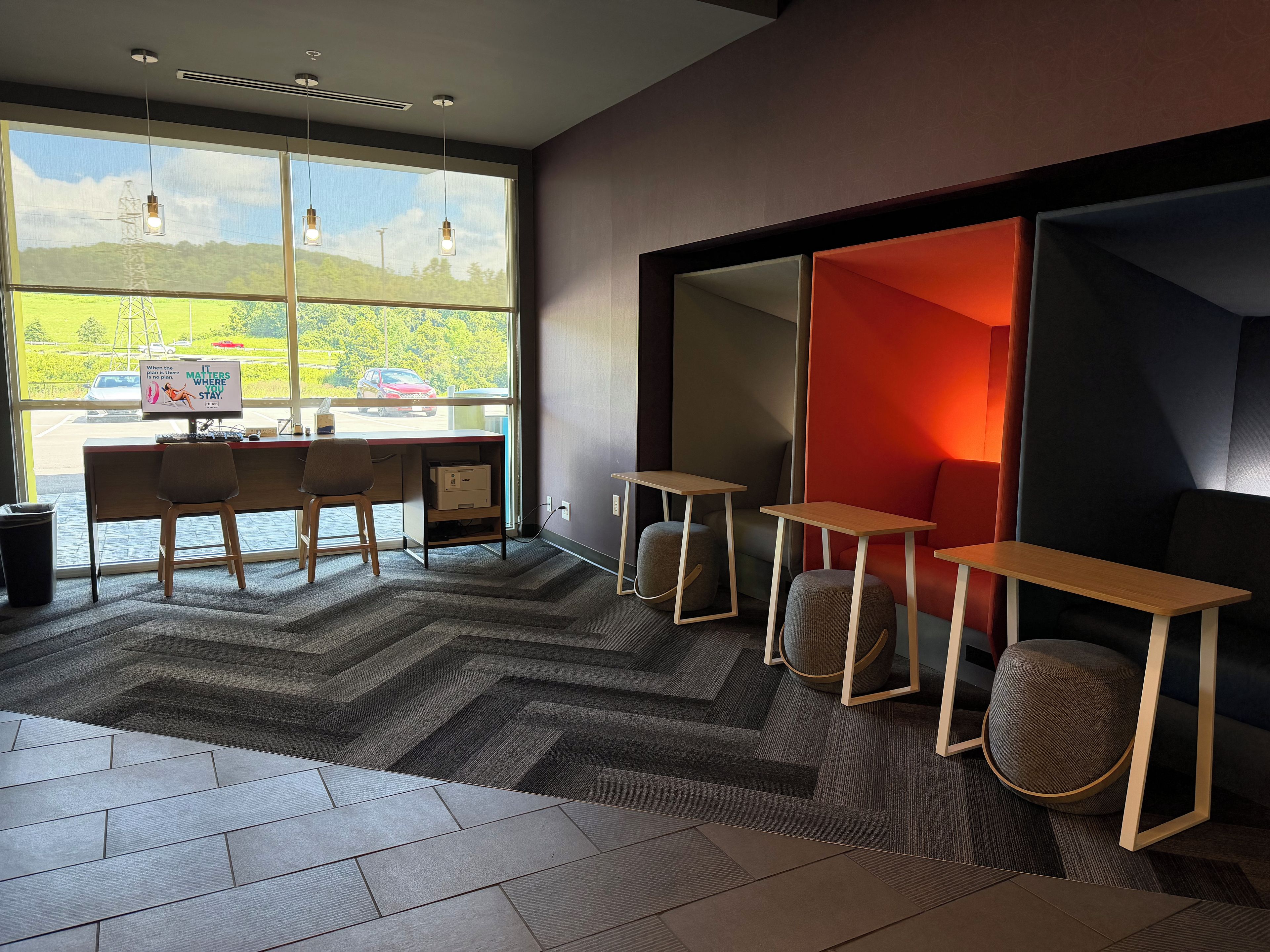 A modern office space with a desk, chairs, and a view of a parking lot.