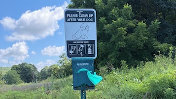 A public trash bin with a sign instructing to clean up after dogs and dispose of waste.