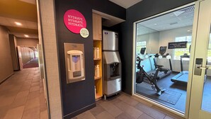 Un centre de remise en forme équipé de matériel d’exercice, de points d’hydratation et d’un panneau indiquant les heures d’ouverture.