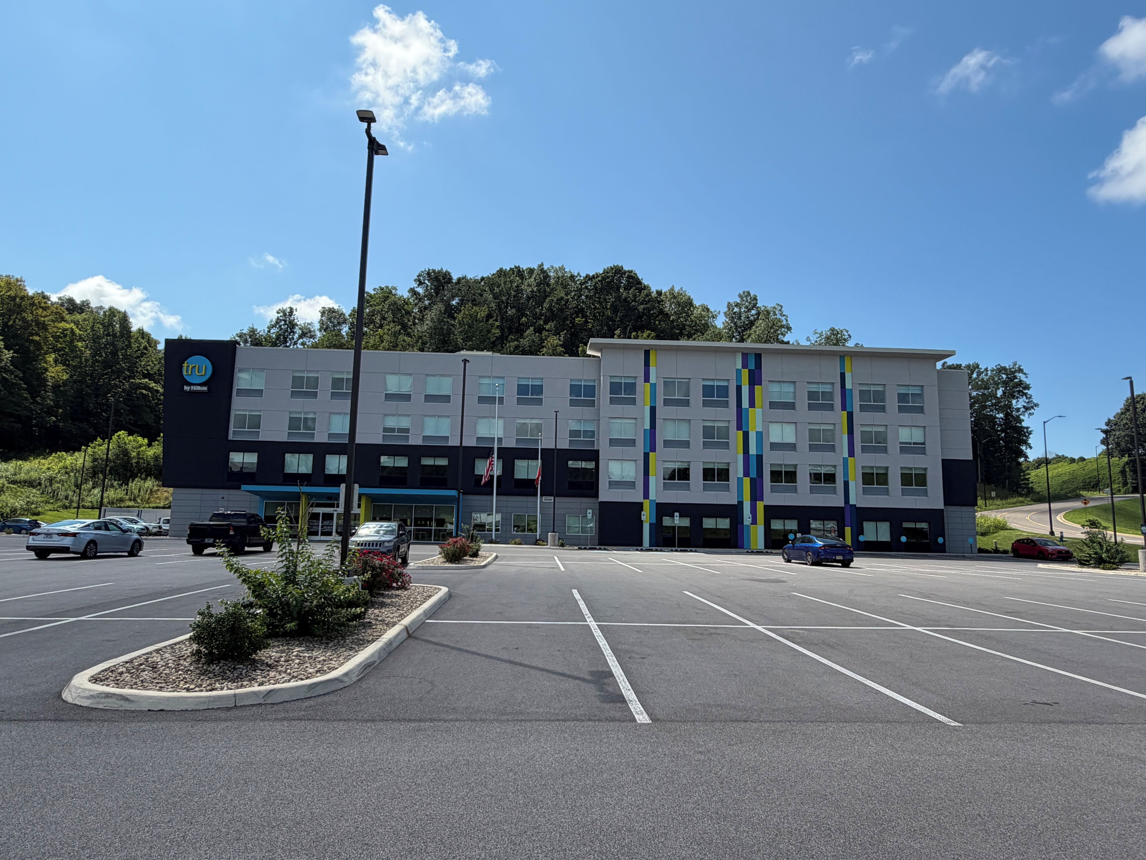 A multi-story hotel with a parking lot in front.