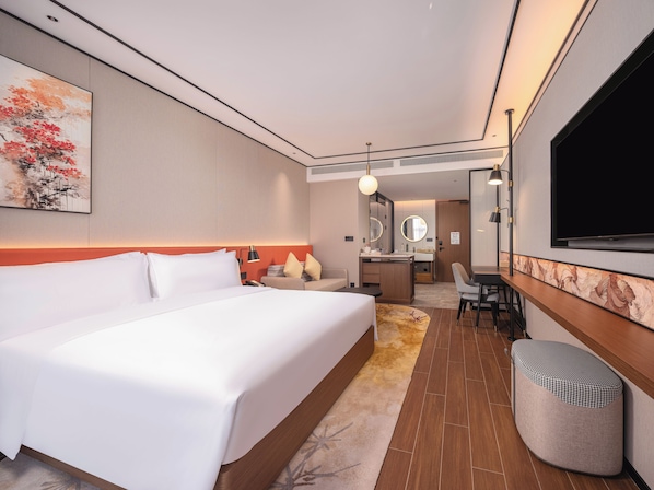 Una habitación de hotel con una cama grande, un escritorio con silla, televisión y baño.