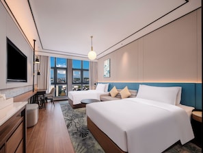 A hotel room with two beds, a desk, a chair, a TV, and a large window with a city view. - Hilton Garden Inn Huangshan Huizhou (Huangshan)