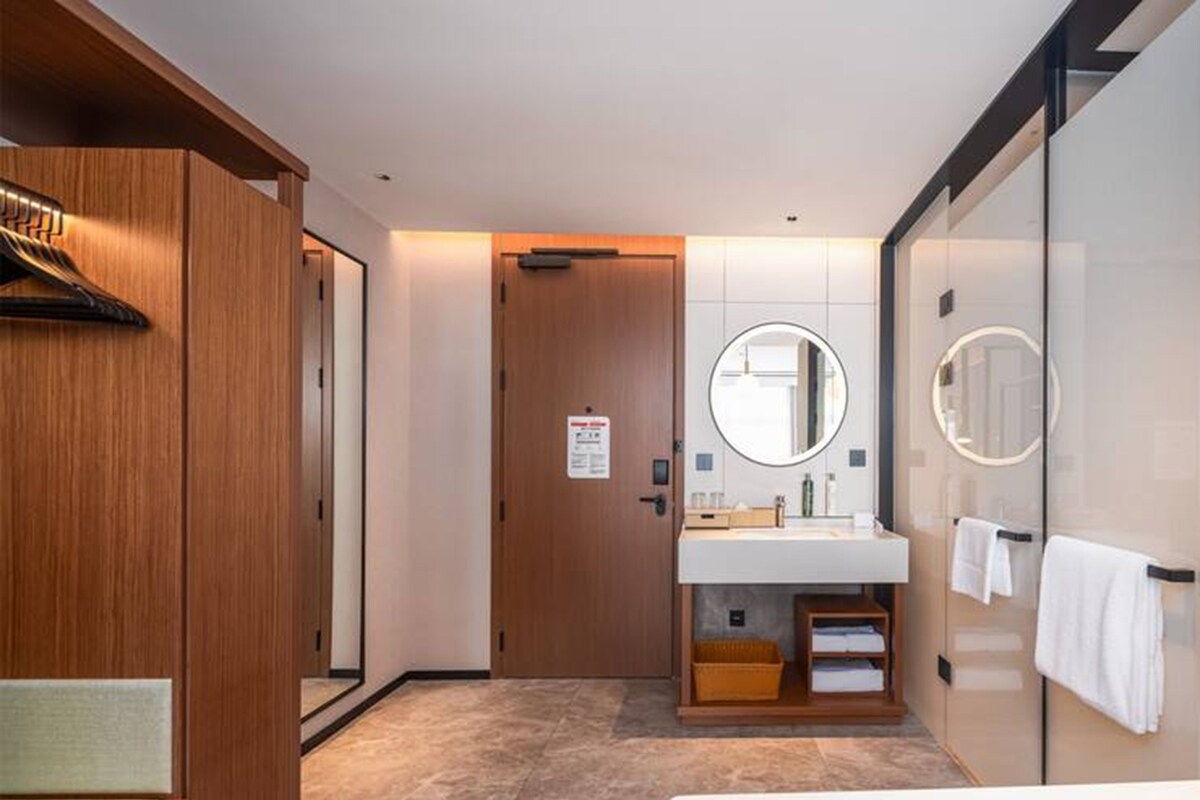 A hotel bathroom with a wooden vanity, a mirror, and a towel rack.