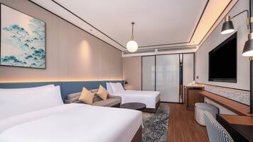 Habitación de hotel con dos camas, un escritorio, un televisor y un cuadro en la pared.