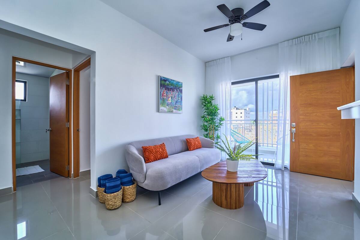 A modern living room with a grey sofa, a wooden coffee table, and a ceiling fan.