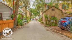 Eine enge Straße gesäumt von historischen Gebäuden, ein geparktes Auto und ein Fußweg.