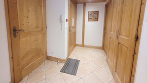 Un pasillo con puertas de madera, un teléfono en la pared y piso de baldosas.