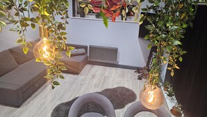 A modern living room with a grey sofa, a round grey chair, and a small table. There are hanging plants and a radiator in the background. - Adorable 2-bedroom apartment in Southampton (Southampton)