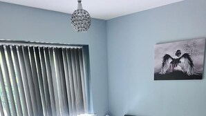 A bedroom with a bed, a radiator, a nightstand, a wall-mounted light fixture, and a painting. - Adorable 2-bedroom apartment in Southampton (Southampton)